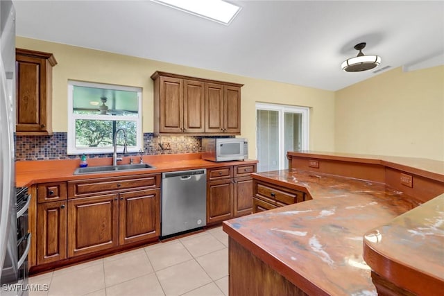 kitchen featuring decorative backsplash, sink, light tile patterned flooring, and stainless steel dishwasher