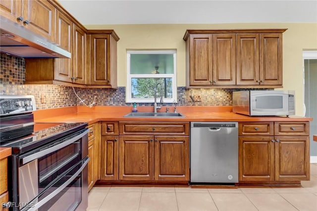 kitchen with decorative backsplash, sink, light tile patterned floors, and stainless steel appliances