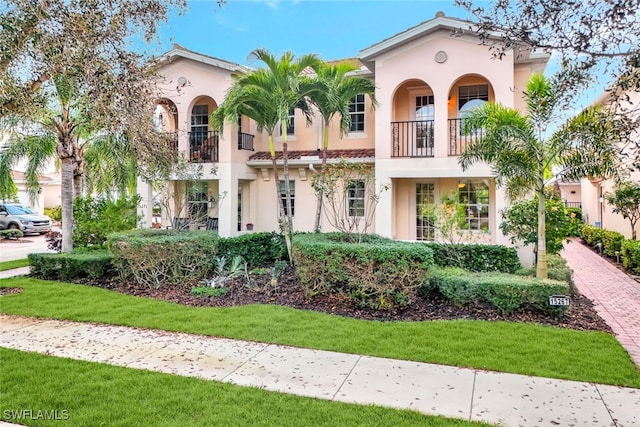 mediterranean / spanish house featuring a front lawn and a balcony