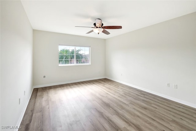 empty room with ceiling fan, baseboards, and wood finished floors