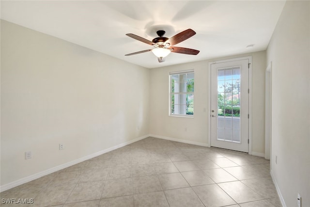 empty room with baseboards, a ceiling fan, and light tile patterned flooring