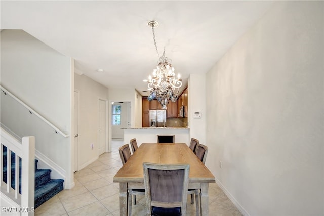 dining area with light tile patterned floors, baseboards, stairway, and a chandelier