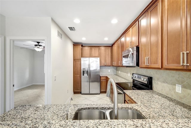 kitchen with sink, backsplash, stainless steel appliances, light stone countertops, and light tile patterned flooring