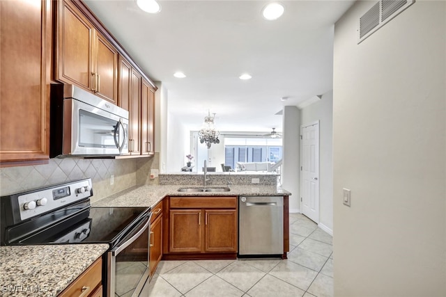 kitchen with sink, light tile patterned floors, stainless steel appliances, light stone countertops, and decorative backsplash