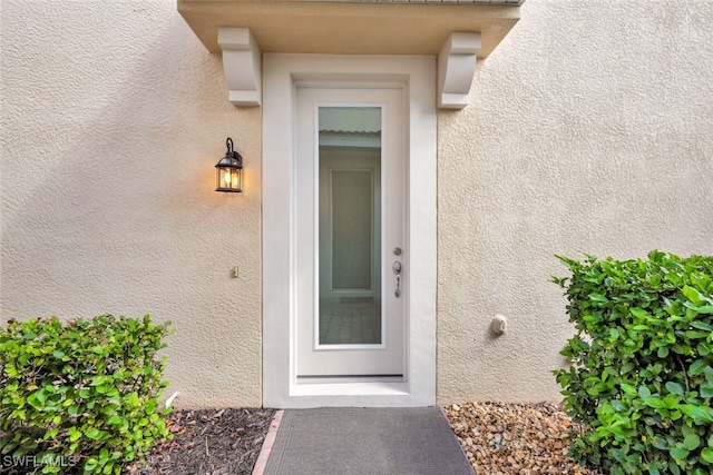 doorway to property featuring stucco siding