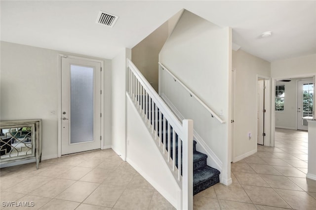 foyer with stairs, light tile patterned flooring, visible vents, and baseboards