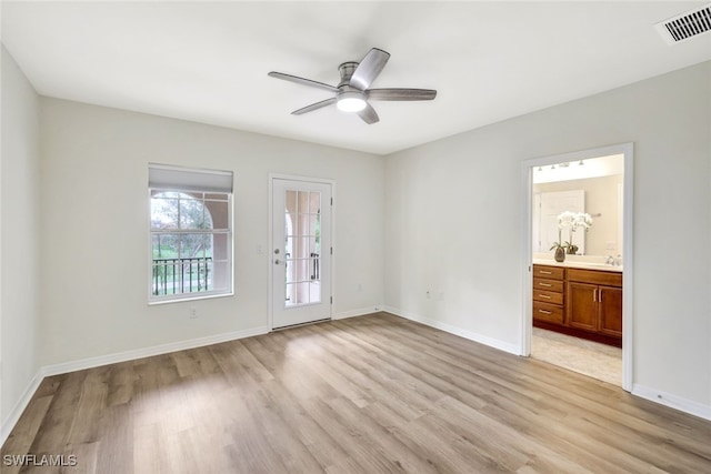 interior space with ensuite bathroom, visible vents, baseboards, access to exterior, and light wood-style floors