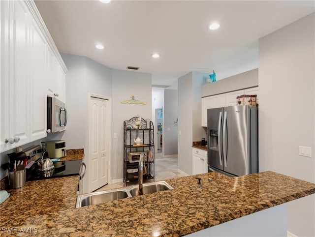 kitchen featuring sink, white cabinets, dark stone countertops, kitchen peninsula, and appliances with stainless steel finishes