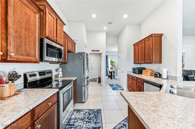 kitchen featuring kitchen peninsula, sink, light tile patterned flooring, and stainless steel appliances