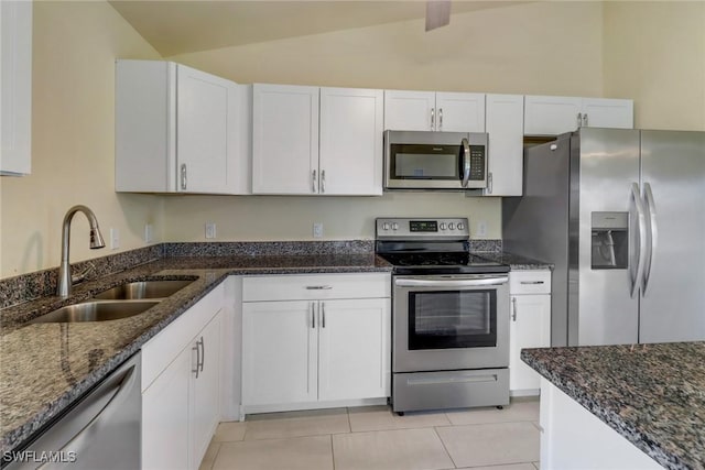 kitchen with dark stone counters, white cabinets, sink, vaulted ceiling with beams, and stainless steel appliances