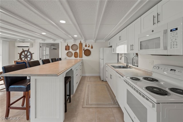 kitchen featuring sink, a wall mounted AC, white appliances, a breakfast bar area, and white cabinets