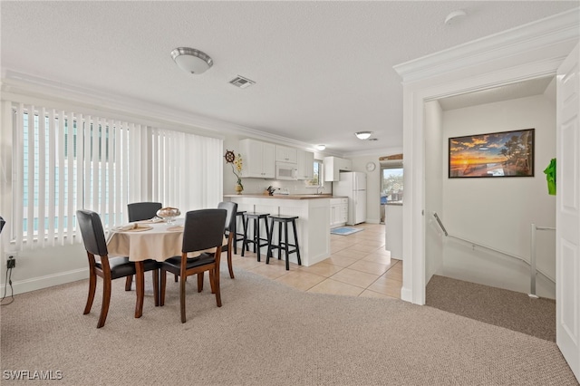 dining space featuring light tile patterned floors, a textured ceiling, and ornamental molding