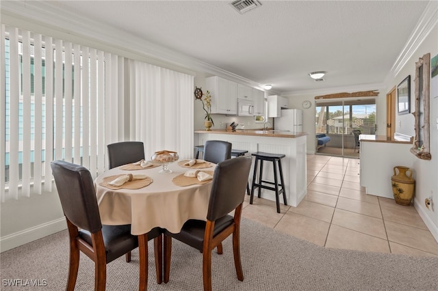 tiled dining area with crown molding and sink