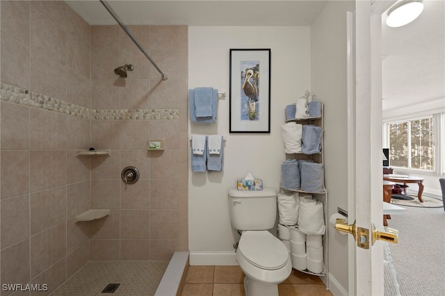 bathroom with tiled shower, tile patterned flooring, and toilet