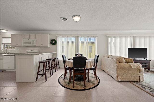 dining space with crown molding, sink, light tile patterned floors, and a textured ceiling