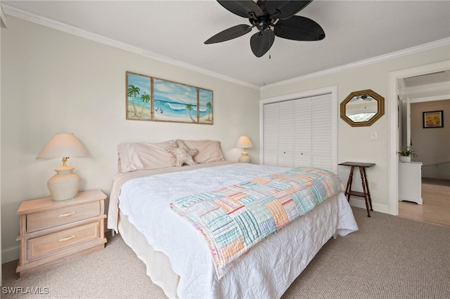 bedroom featuring ceiling fan, a closet, light colored carpet, and ornamental molding