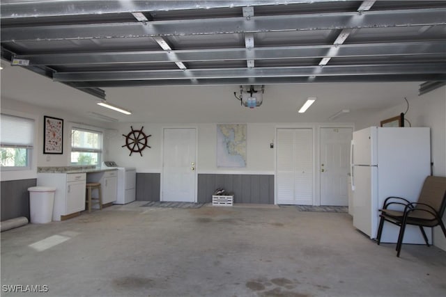 garage featuring white refrigerator, a garage door opener, and washer and clothes dryer