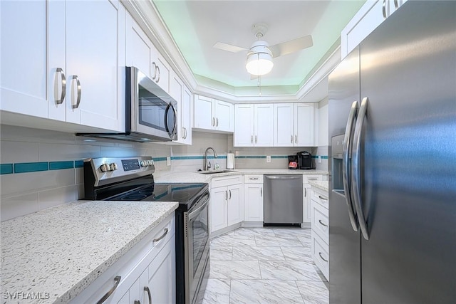 kitchen with tasteful backsplash, ceiling fan, light stone countertops, stainless steel appliances, and white cabinets