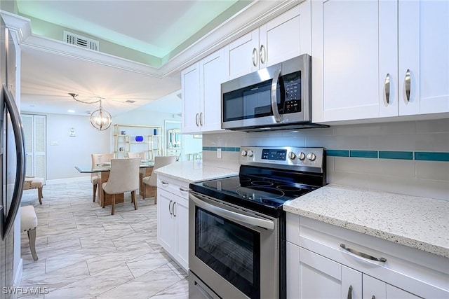 kitchen featuring appliances with stainless steel finishes, pendant lighting, white cabinets, and tasteful backsplash