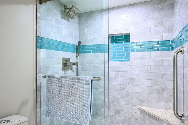 bathroom featuring toilet and a shower with door