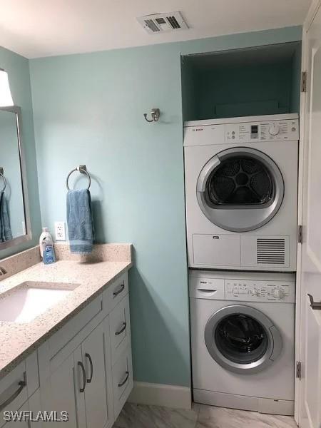 laundry room with sink and stacked washer / drying machine