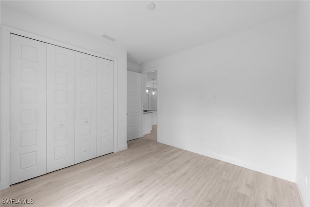 unfurnished bedroom featuring a closet and light wood-type flooring