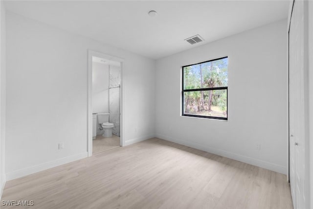 unfurnished bedroom with light wood-type flooring and ensuite bath