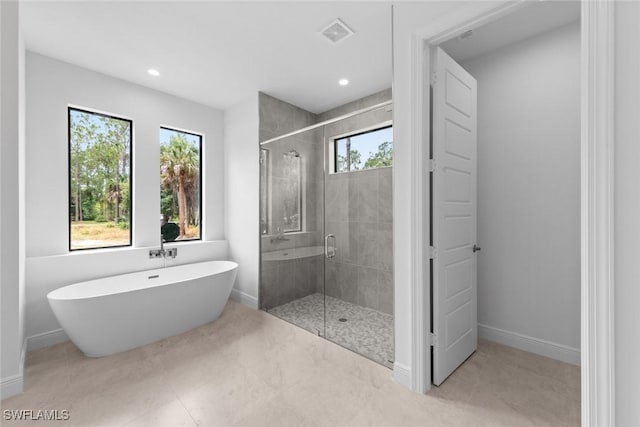 bathroom featuring a wealth of natural light and shower with separate bathtub