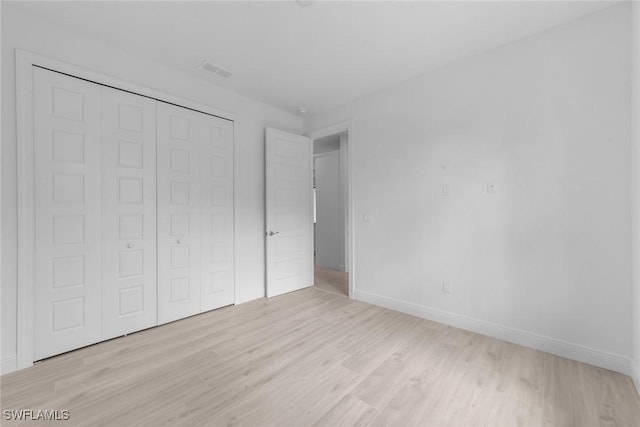 unfurnished bedroom with a closet and light hardwood / wood-style floors