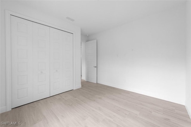 unfurnished bedroom with light wood-type flooring and a closet