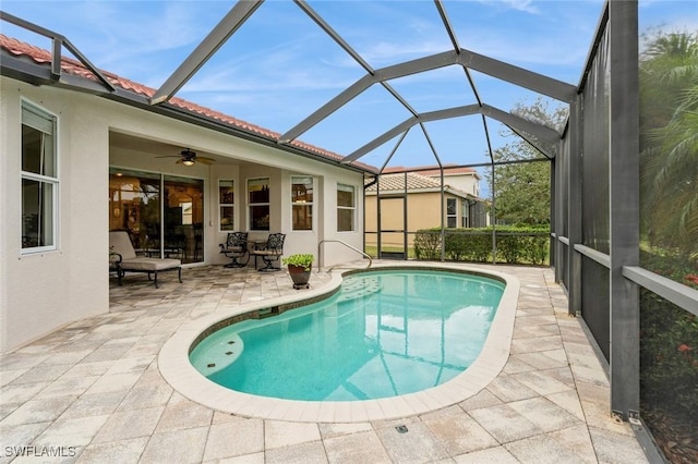 view of swimming pool with glass enclosure, ceiling fan, and a patio