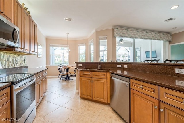 kitchen featuring sink, hanging light fixtures, ceiling fan, dark stone countertops, and appliances with stainless steel finishes