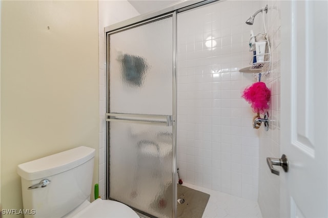 bathroom featuring a shower with shower door and toilet