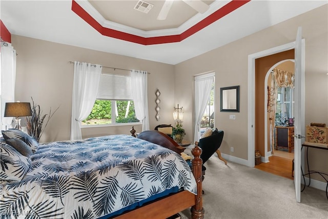 carpeted bedroom with a tray ceiling, ceiling fan, and ornamental molding