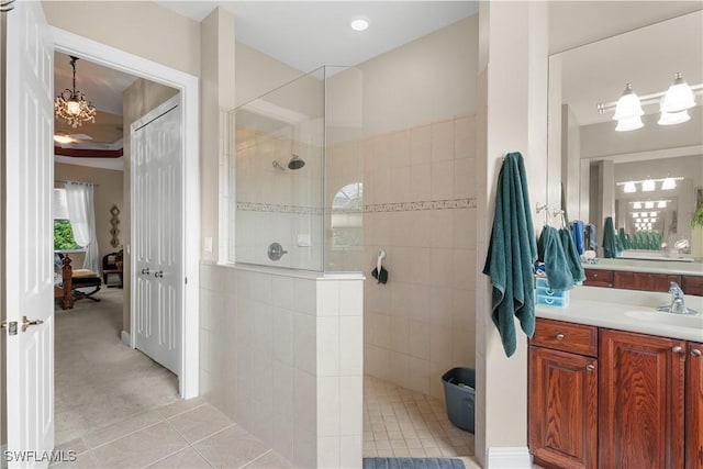 bathroom with tile patterned flooring, vanity, tiled shower, and an inviting chandelier