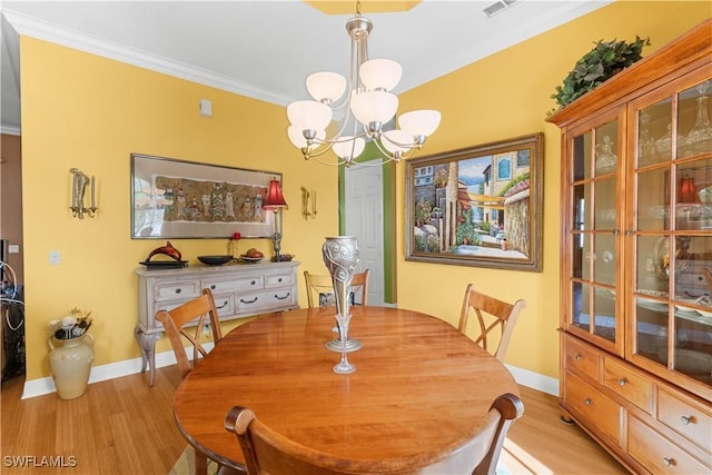 dining area with light wood-type flooring, ornamental molding, and a notable chandelier