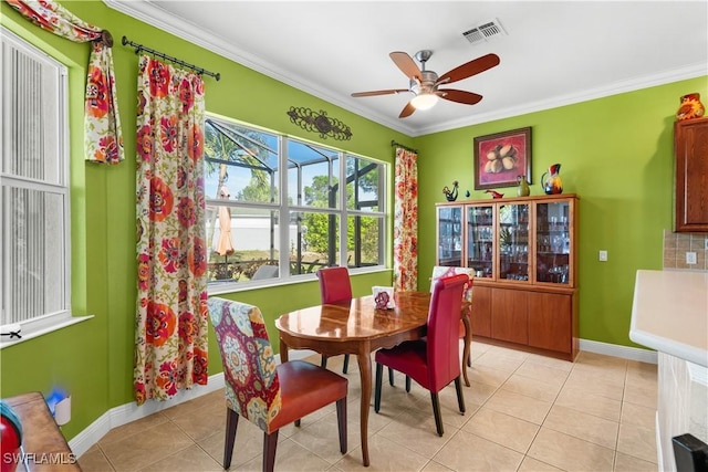 tiled dining space featuring ceiling fan and ornamental molding