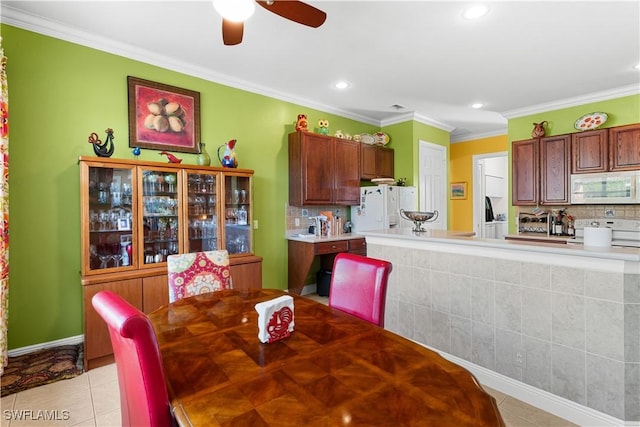 tiled dining room with ceiling fan and crown molding