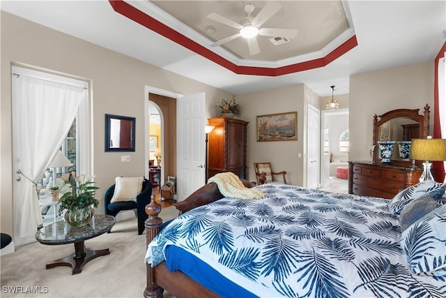 bedroom with light colored carpet, a raised ceiling, ceiling fan, multiple windows, and connected bathroom