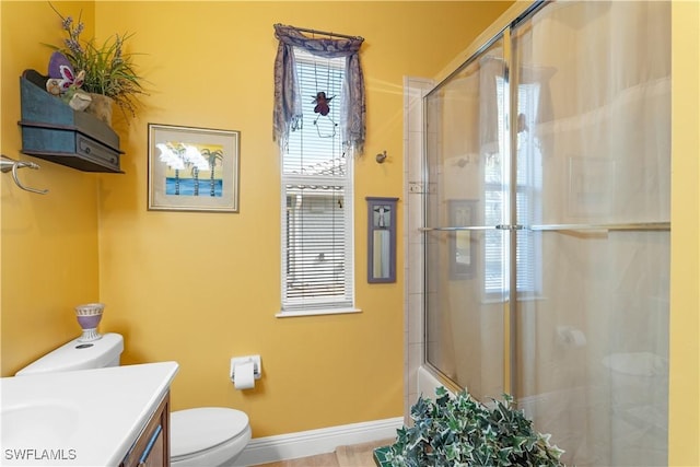 bathroom featuring toilet, plenty of natural light, baseboards, and vanity