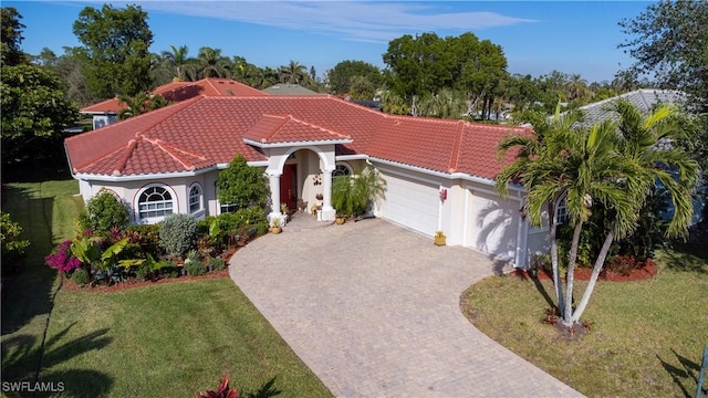 mediterranean / spanish house with a tiled roof, decorative driveway, an attached garage, and stucco siding