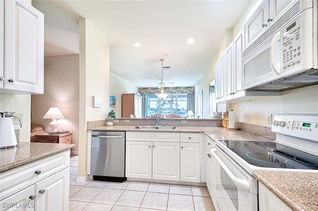 kitchen featuring white appliances, light stone counters, white cabinetry, a sink, and light tile patterned flooring