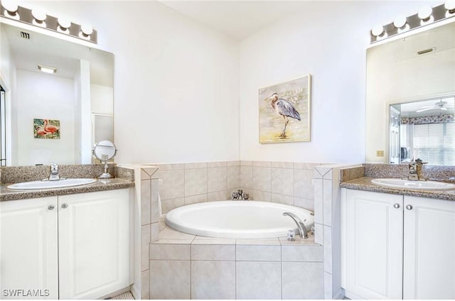 bathroom featuring a garden tub, two vanities, and a sink