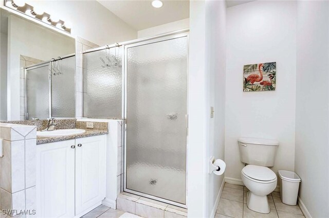 bathroom featuring tile patterned flooring, toilet, and a shower with door