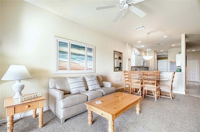 living room with visible vents, ceiling fan, light carpet, and baseboards