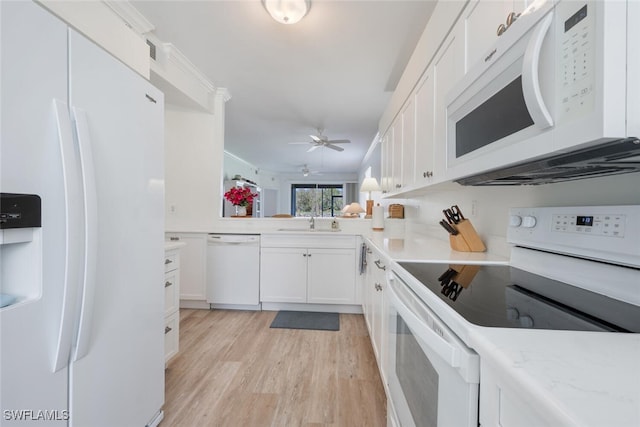 kitchen featuring ornamental molding, white appliances, sink, light hardwood / wood-style floors, and white cabinetry