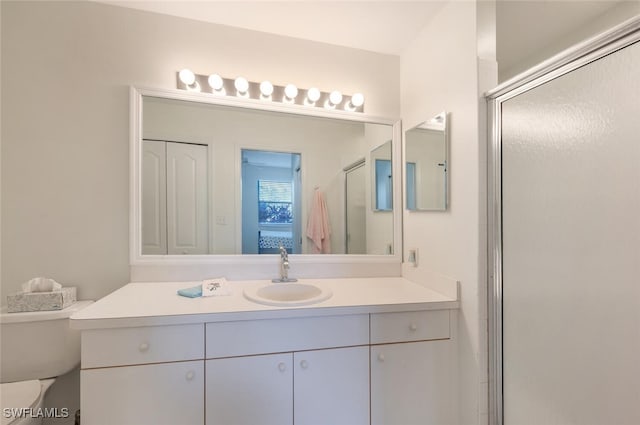 bathroom featuring toilet, vanity, and walk in shower