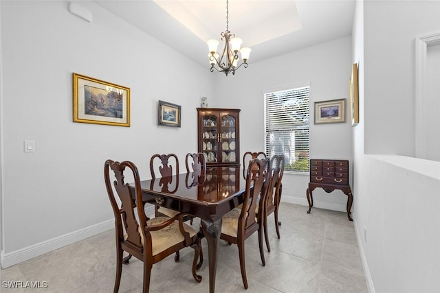 dining space featuring light tile patterned floors, a tray ceiling, and a notable chandelier