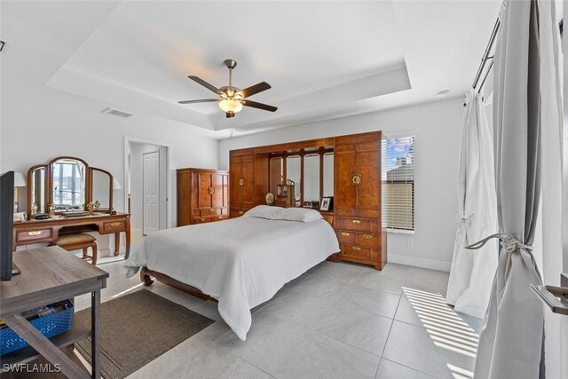 tiled bedroom featuring a raised ceiling and ceiling fan