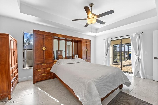 tiled bedroom with access to outside, a tray ceiling, and ceiling fan